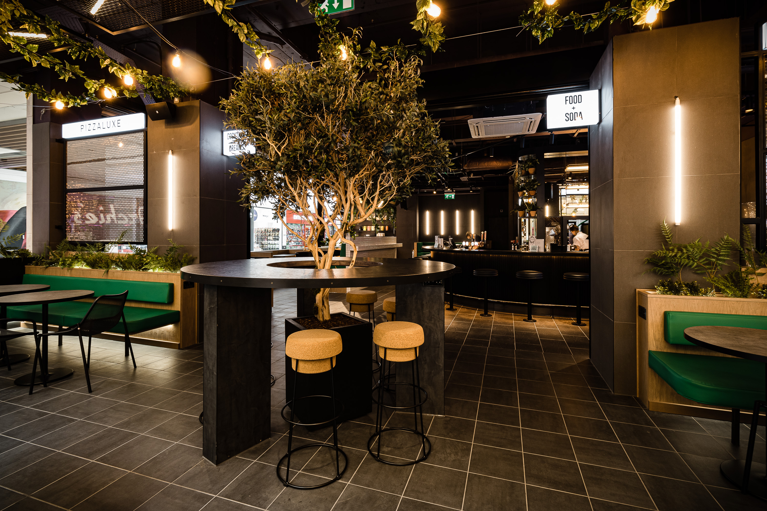 Modern event venue with central bar and greenery in PizzaLuxe Manchester.