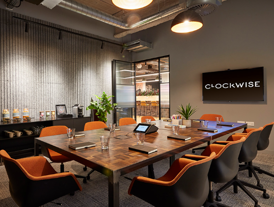 Modern meeting room with wooden table and orange chairs for corporate events.