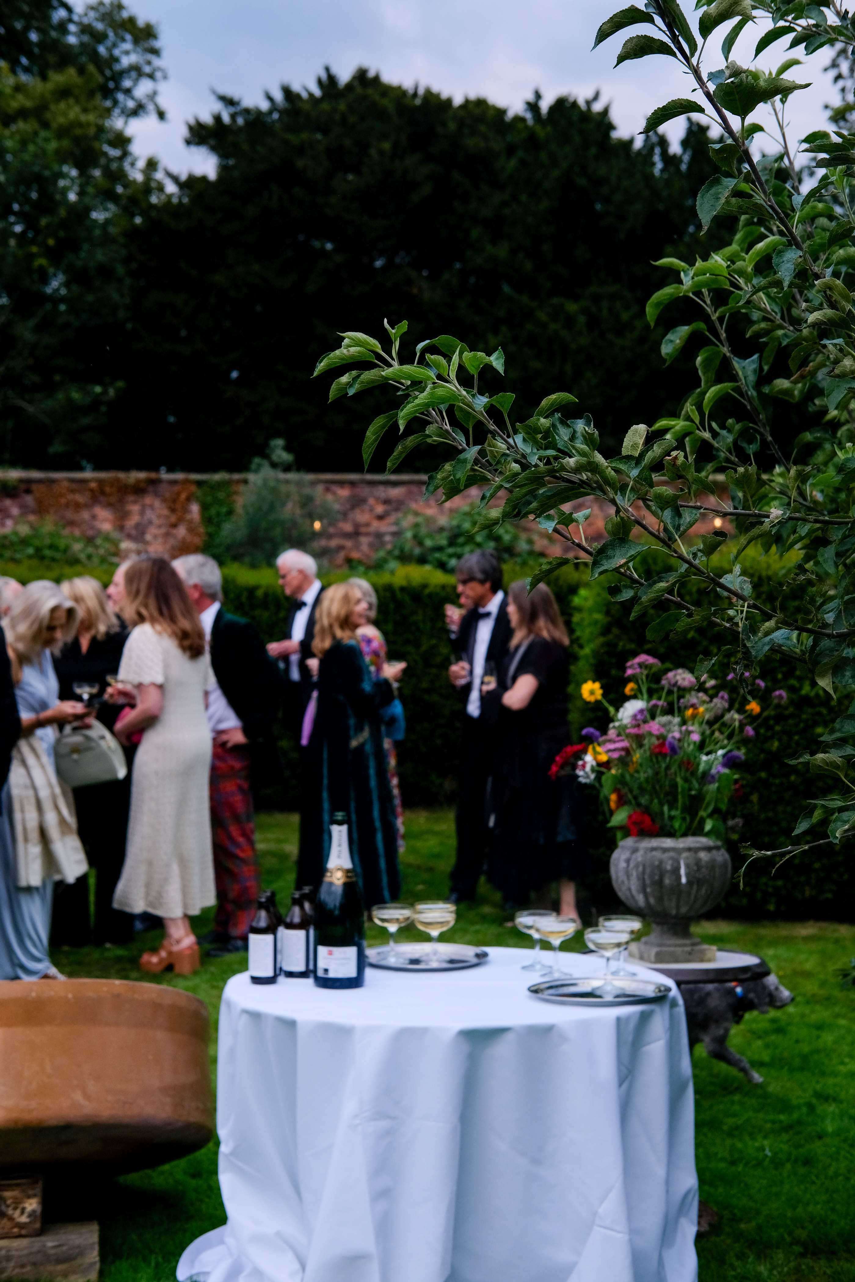Elegant outdoor gala in The Walled Garden, lush greenery and floral arrangements.