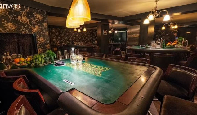 Stylish private hire event space with green felt gaming table and plush seating.