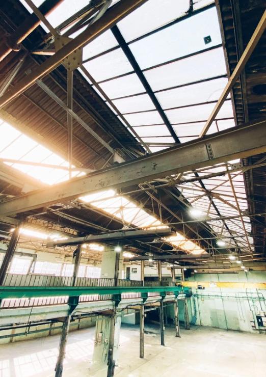 Spacious industrial venue with skylights, ideal for conferences and workshops.