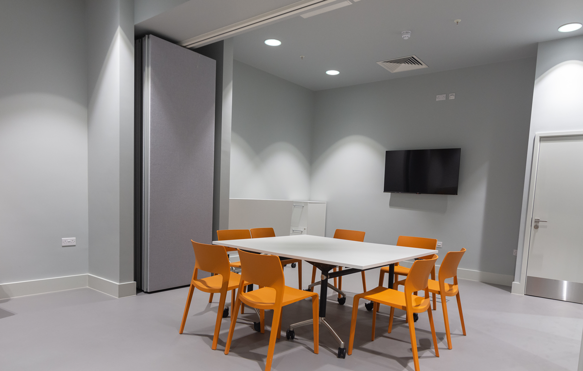 Una Marson Meeting Room 1 with modular table and bright orange chairs for events.