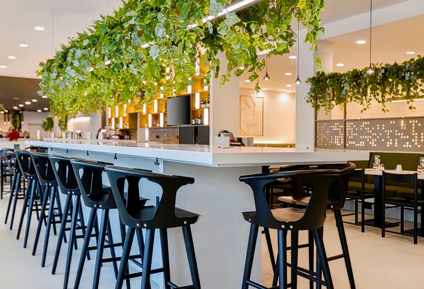 Modern bar area with high stools and greenery, perfect for networking events in Manchester.