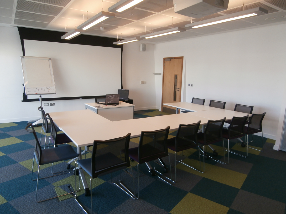 Modern meeting room with L-shaped table, ideal for collaborative discussions and presentations.