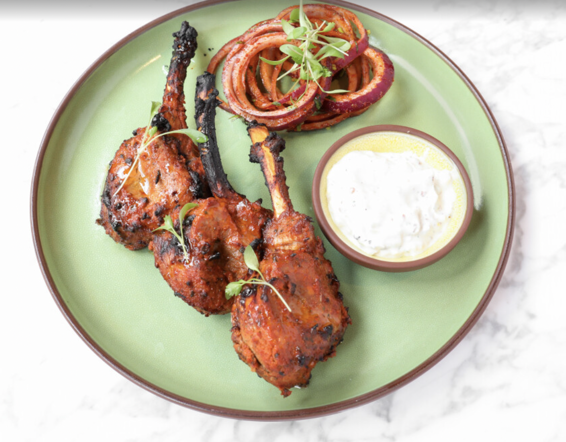 Grilled chicken drumsticks with onion rings at Biryani Kebab Chai, perfect for events.