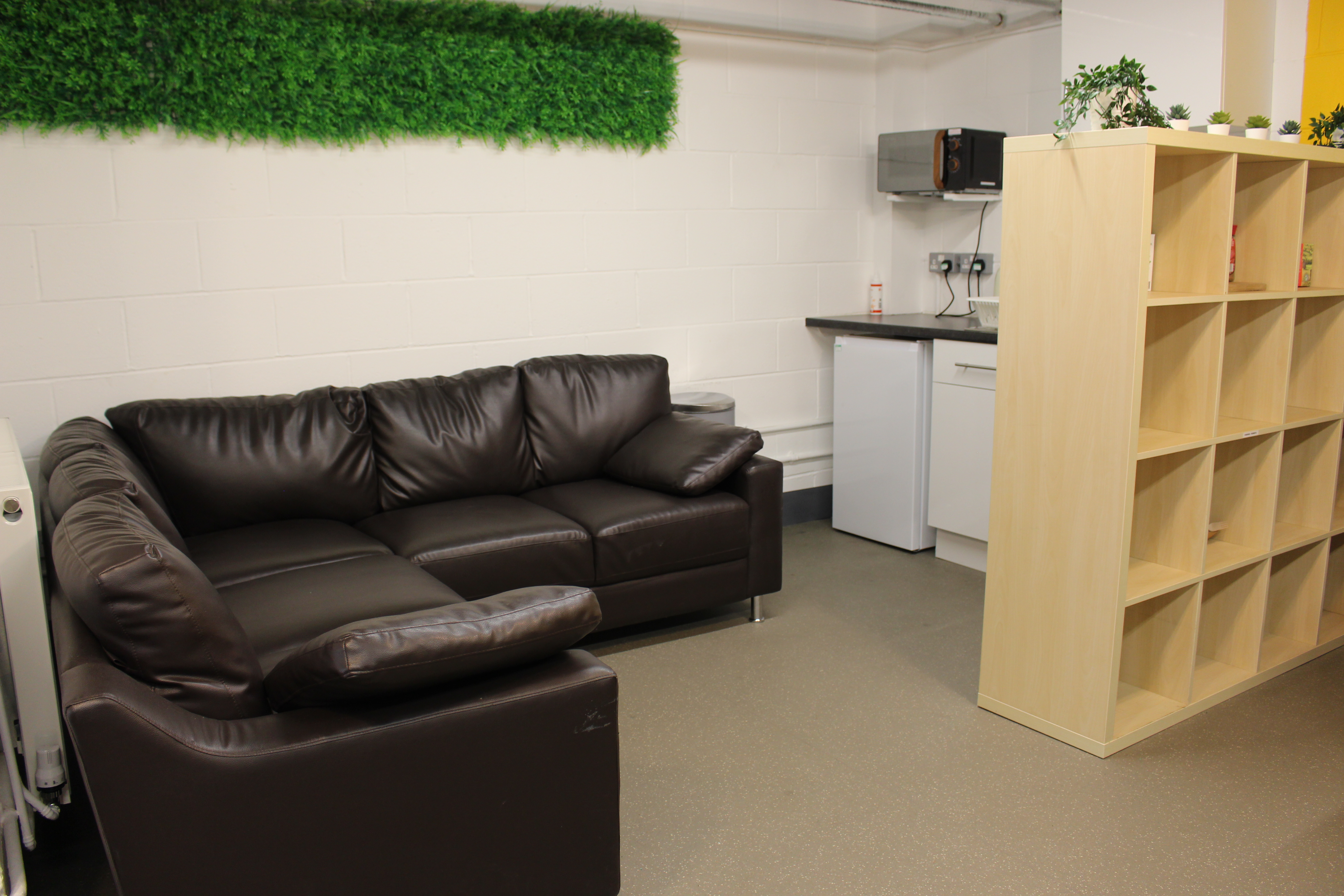 Cozy meeting room with leather couch and kitchenette for networking events in Tooting Works.