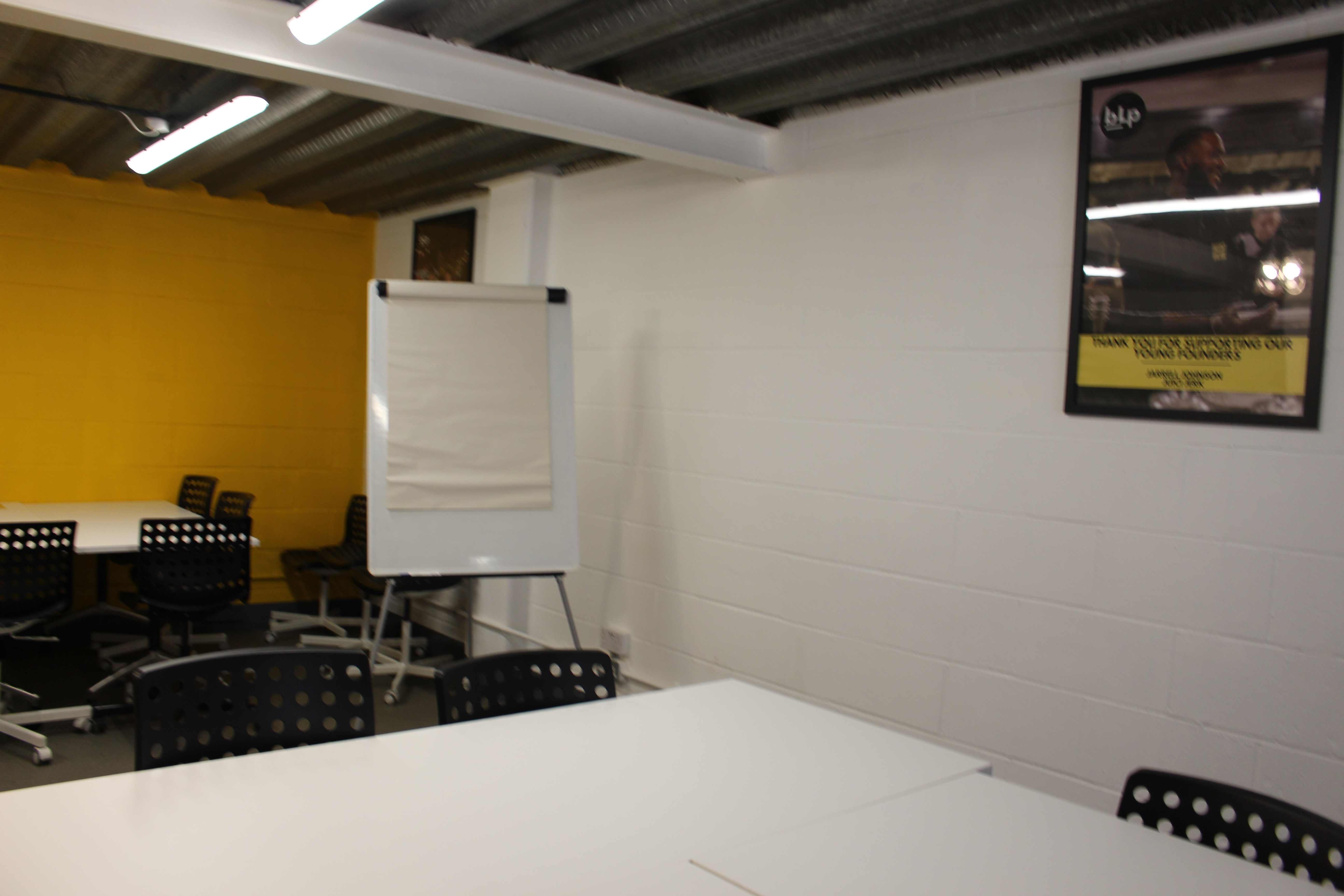 Versatile meeting room in Tooting Works with modular seating and bright yellow accents.