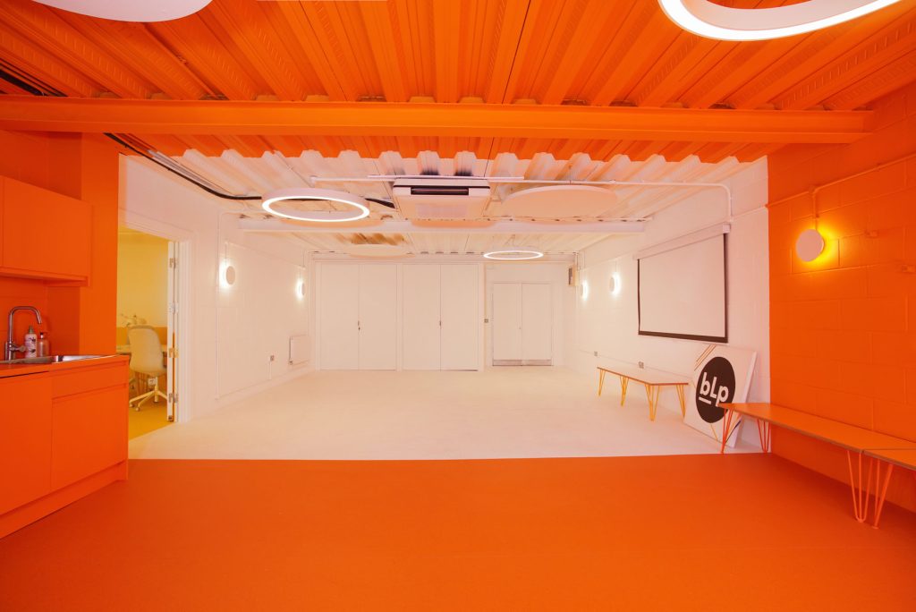 Modern event space in Tooting with vibrant orange flooring for workshops and meetings.