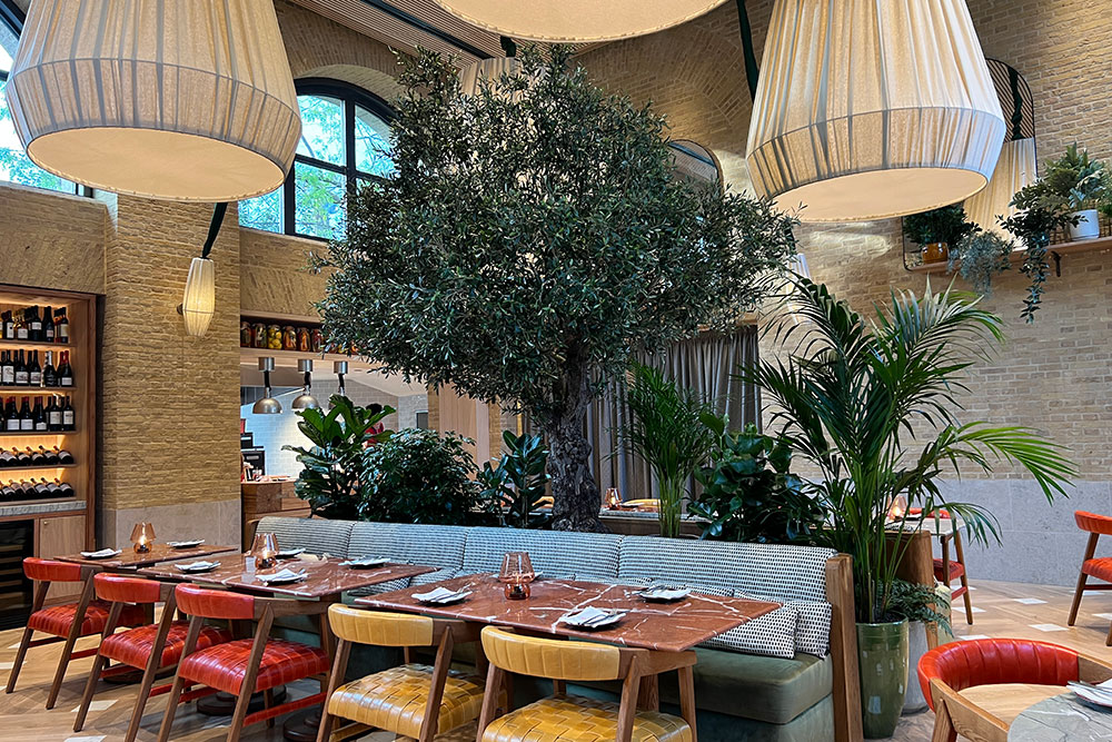 Stylish restaurant with central tree, ideal for intimate meetings and corporate events.