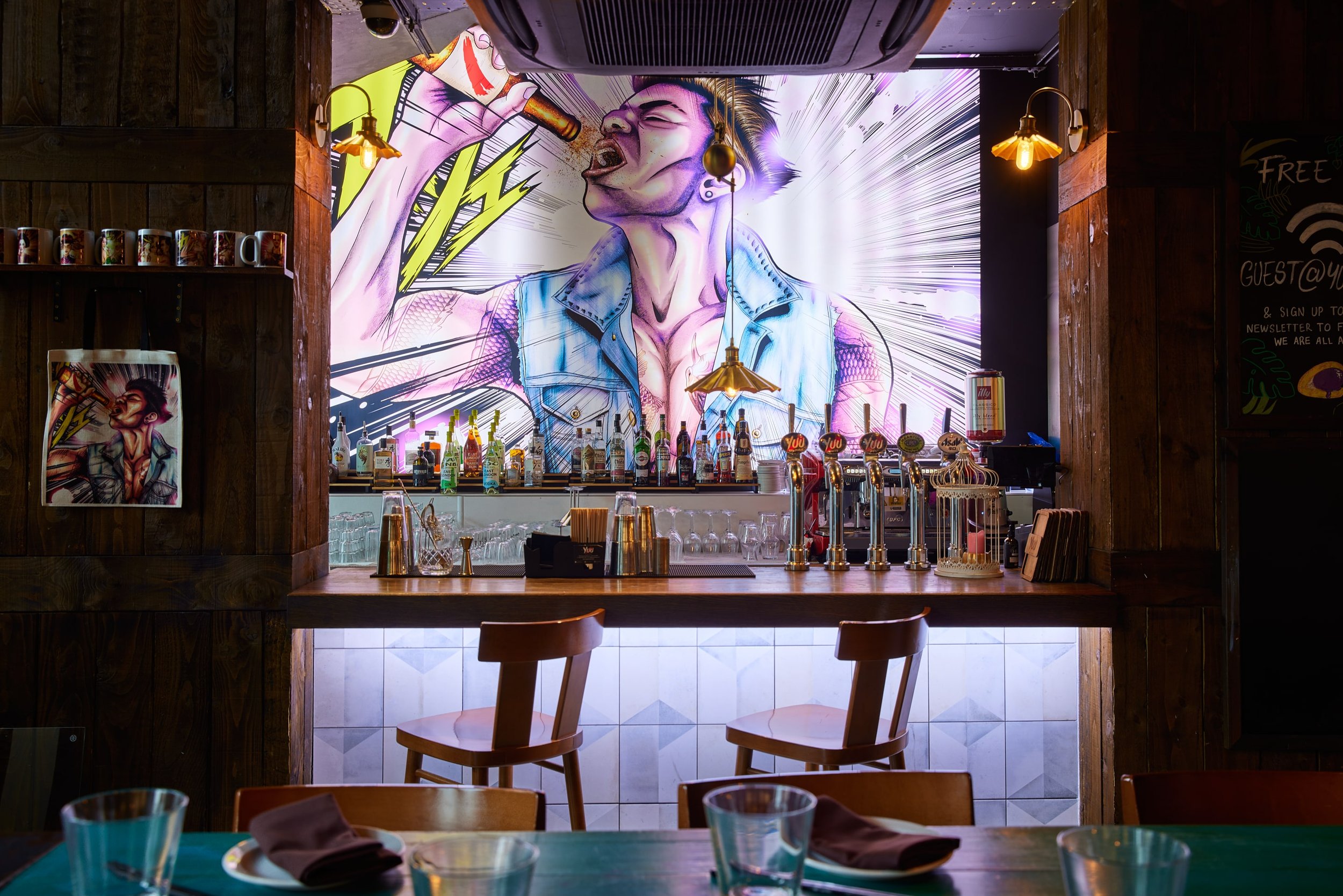 Outdoor terrace bar at Yuu Kitchen with vibrant mural, ideal for social gatherings.