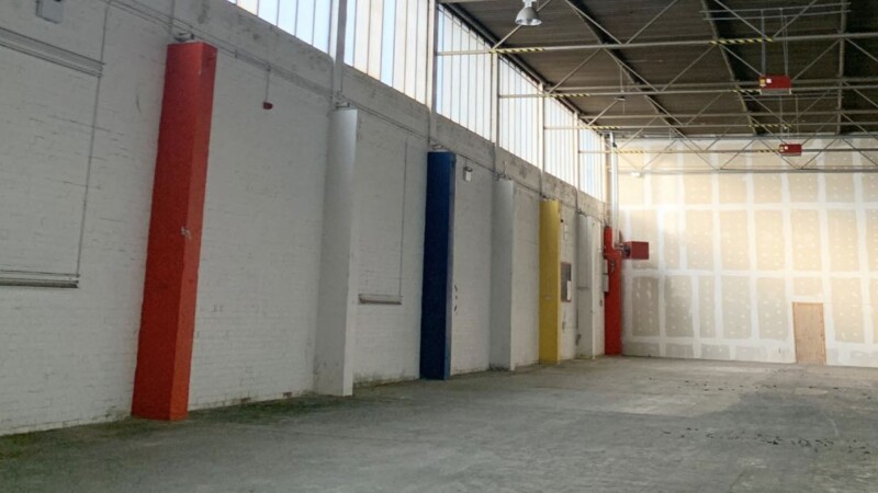 Spacious industrial live music venue with colorful columns for events and exhibitions.