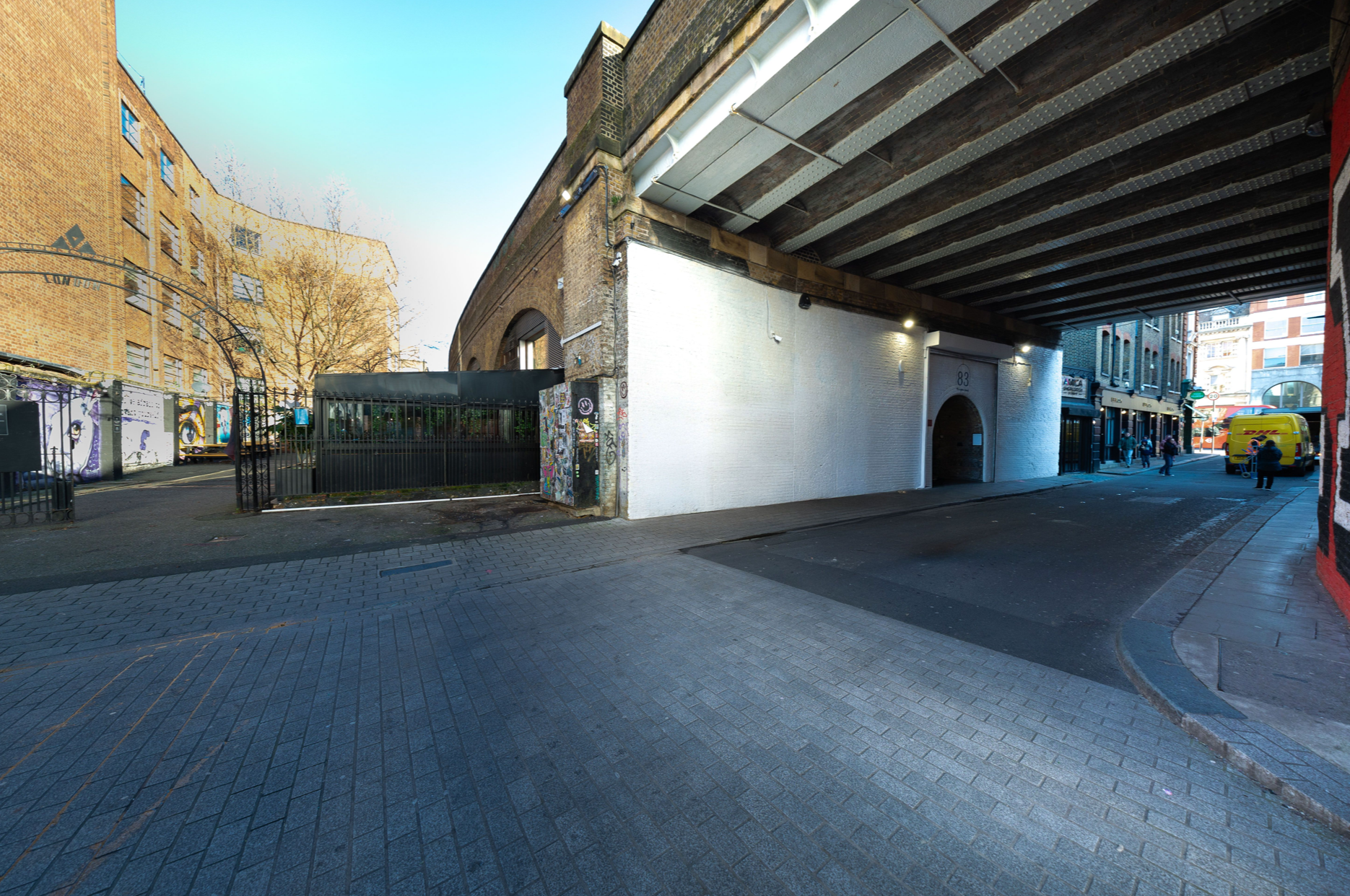 Urban venue under railway arch with graffiti for outdoor events and pop-up markets.