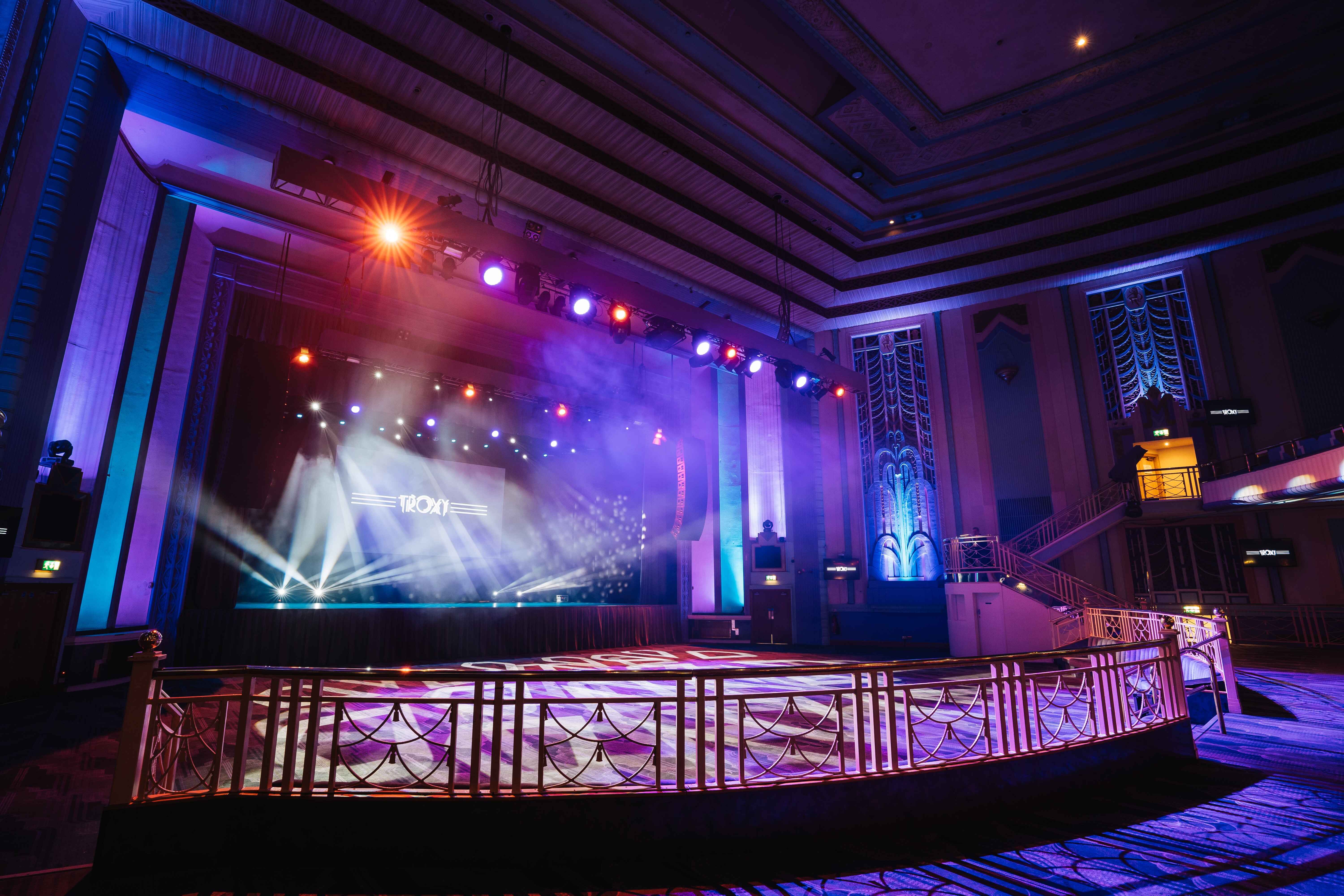 Grand Hall at Troxy: elegant event space with vibrant stage lighting for conferences and concerts.