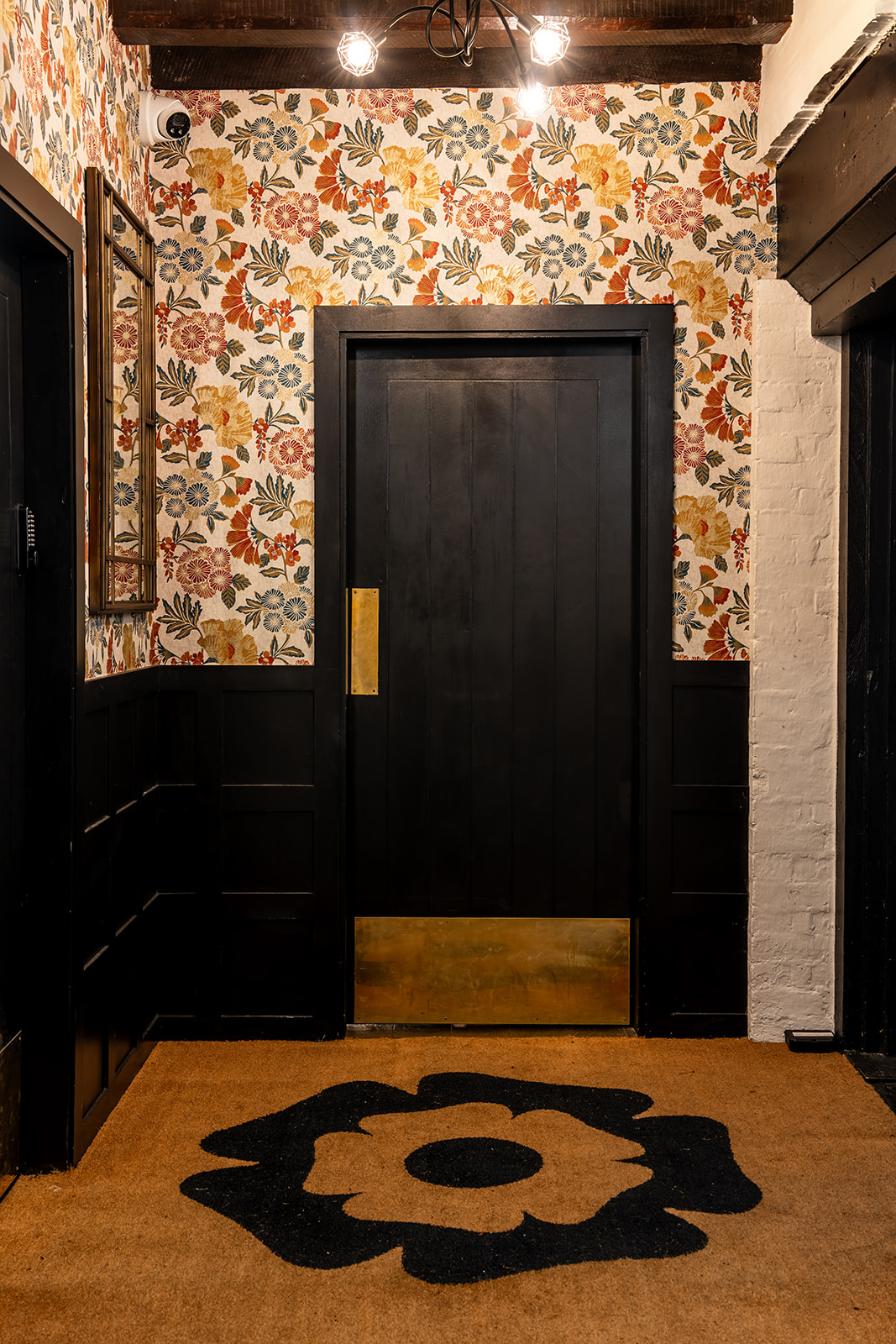 Tudor Barn Eltham entrance with dark wooden door and floral wallpaper, perfect for events.