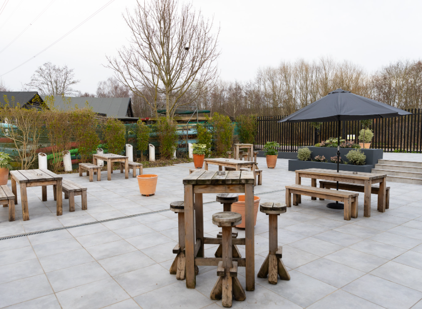 Outdoor event space at The River Garden Cafe Bistro with rustic tables and umbrellas.