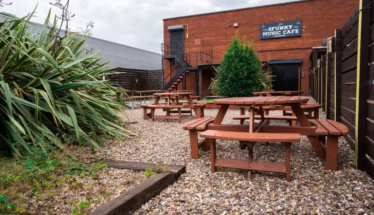 Outdoor event space at 2Funky Lounge with rustic tables, perfect for music gatherings.