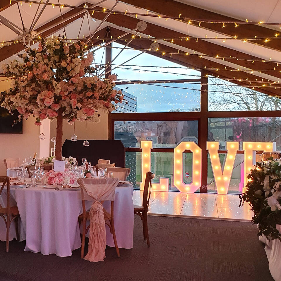 Elegant wedding venue with floral decor and illuminated "LOVE" sign at Clubhouse Bar.