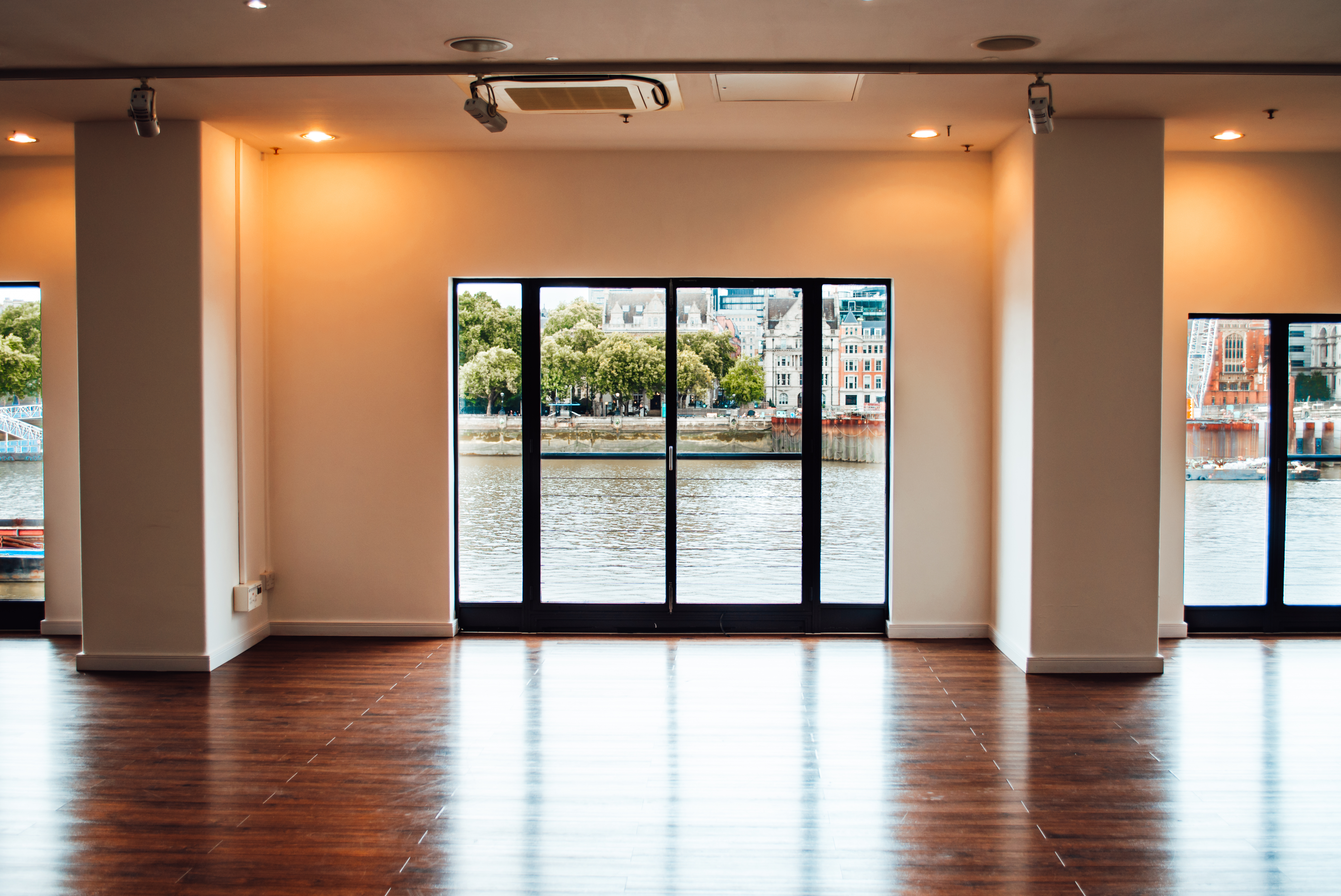 Versatile West Wing event space with large windows and polished wooden floor, ideal for gatherings.