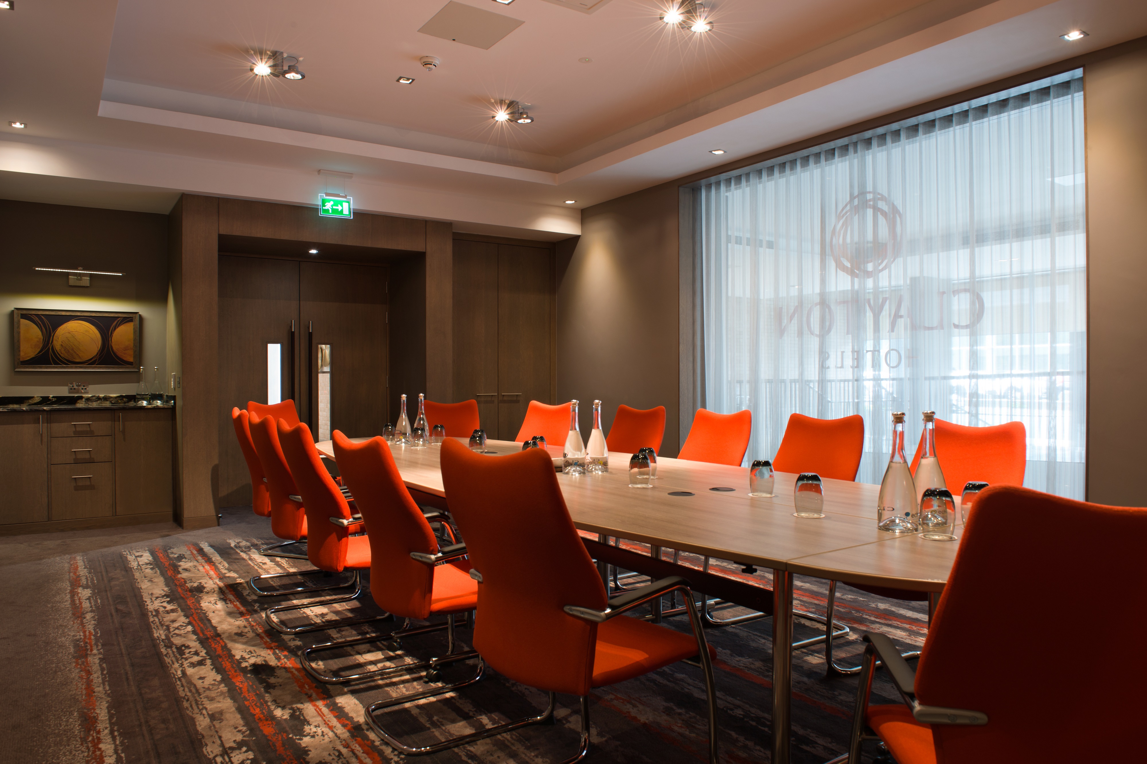 Modern meeting room at Clayton Hotel Chiswick with vibrant orange chairs for corporate events.