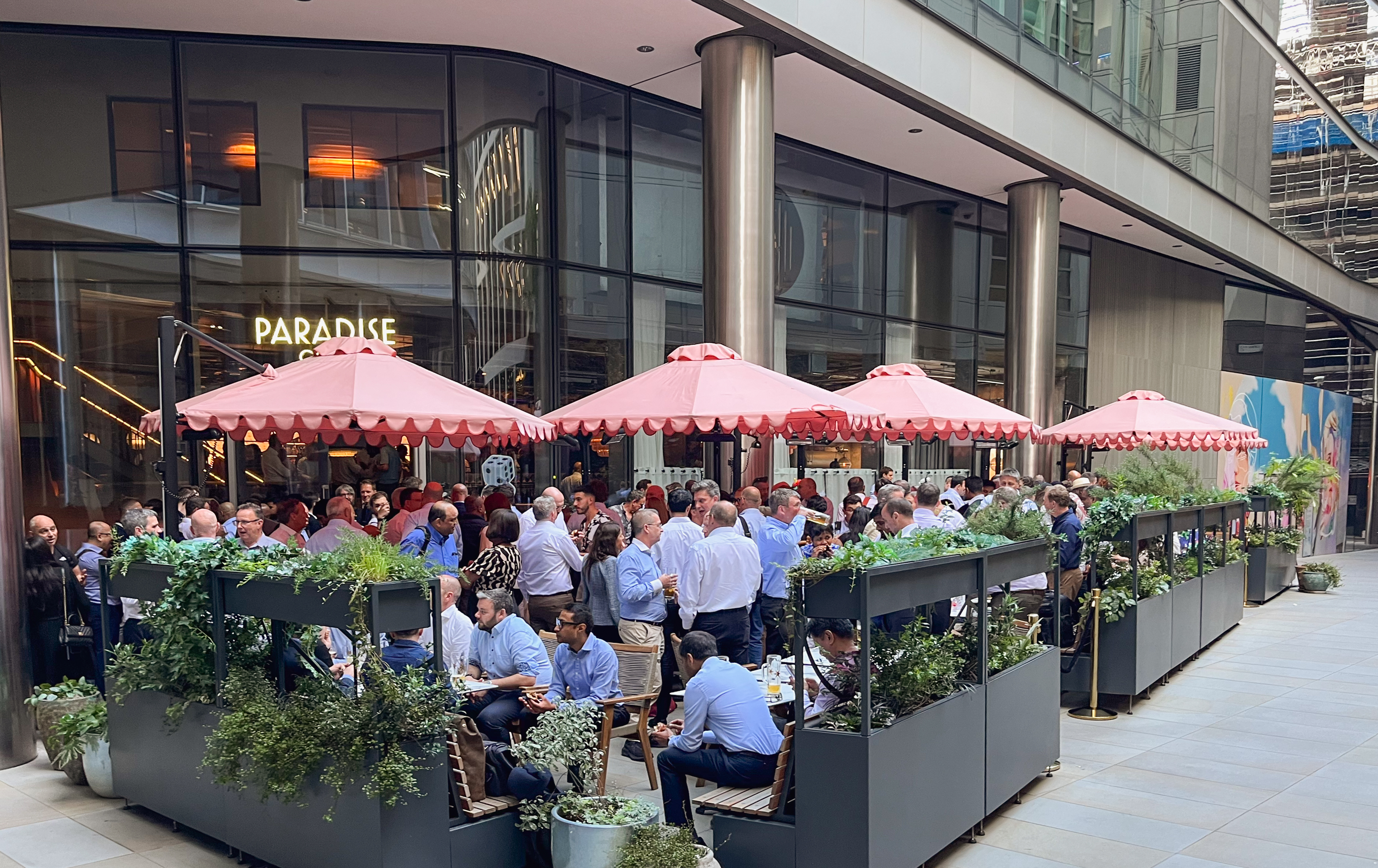 Vibrant outdoor venue hire with greenery and pink umbrellas for networking events.