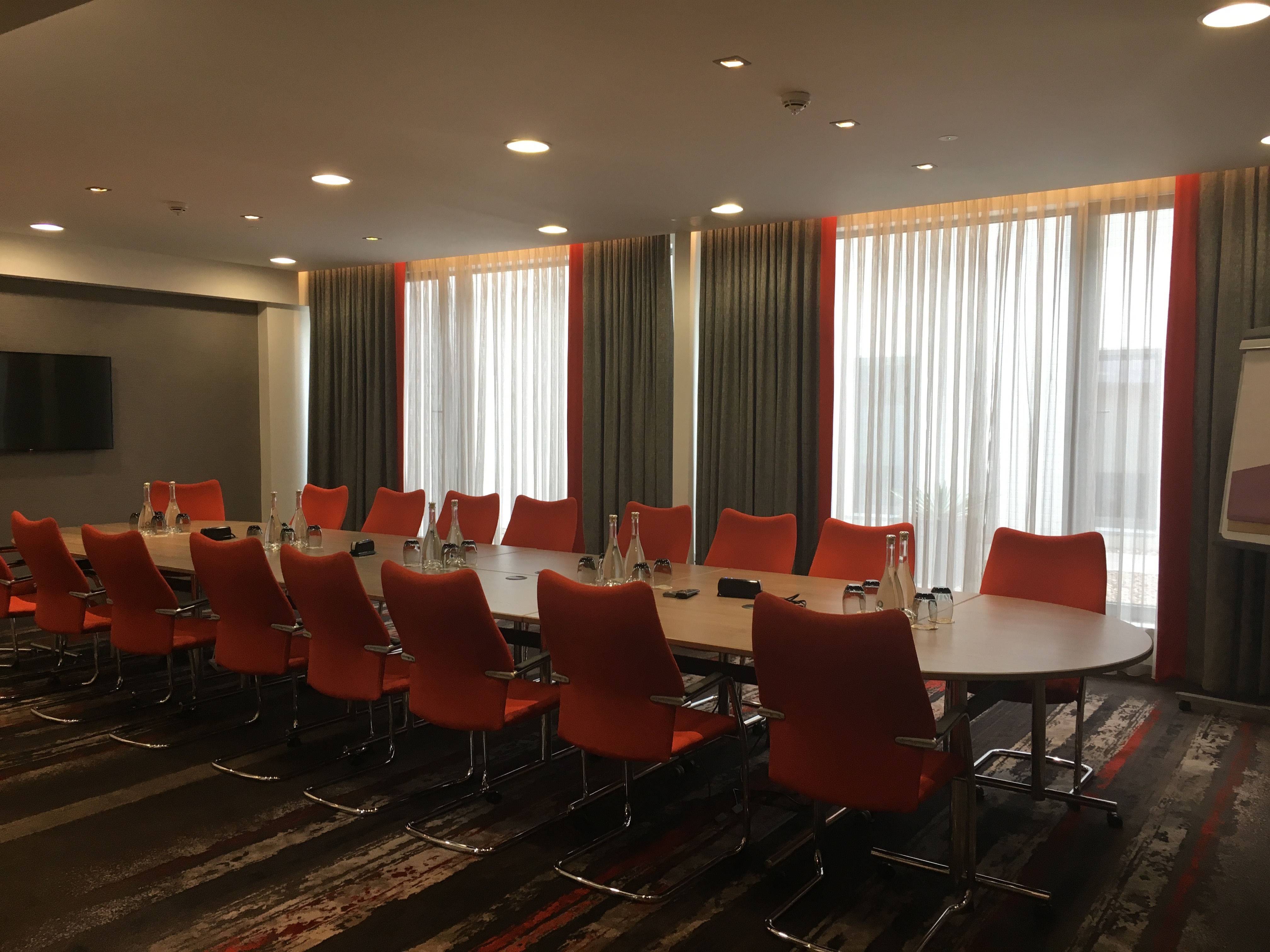 Modern Gunnersbury Suite meeting room with orange chairs and natural light, ideal for events.