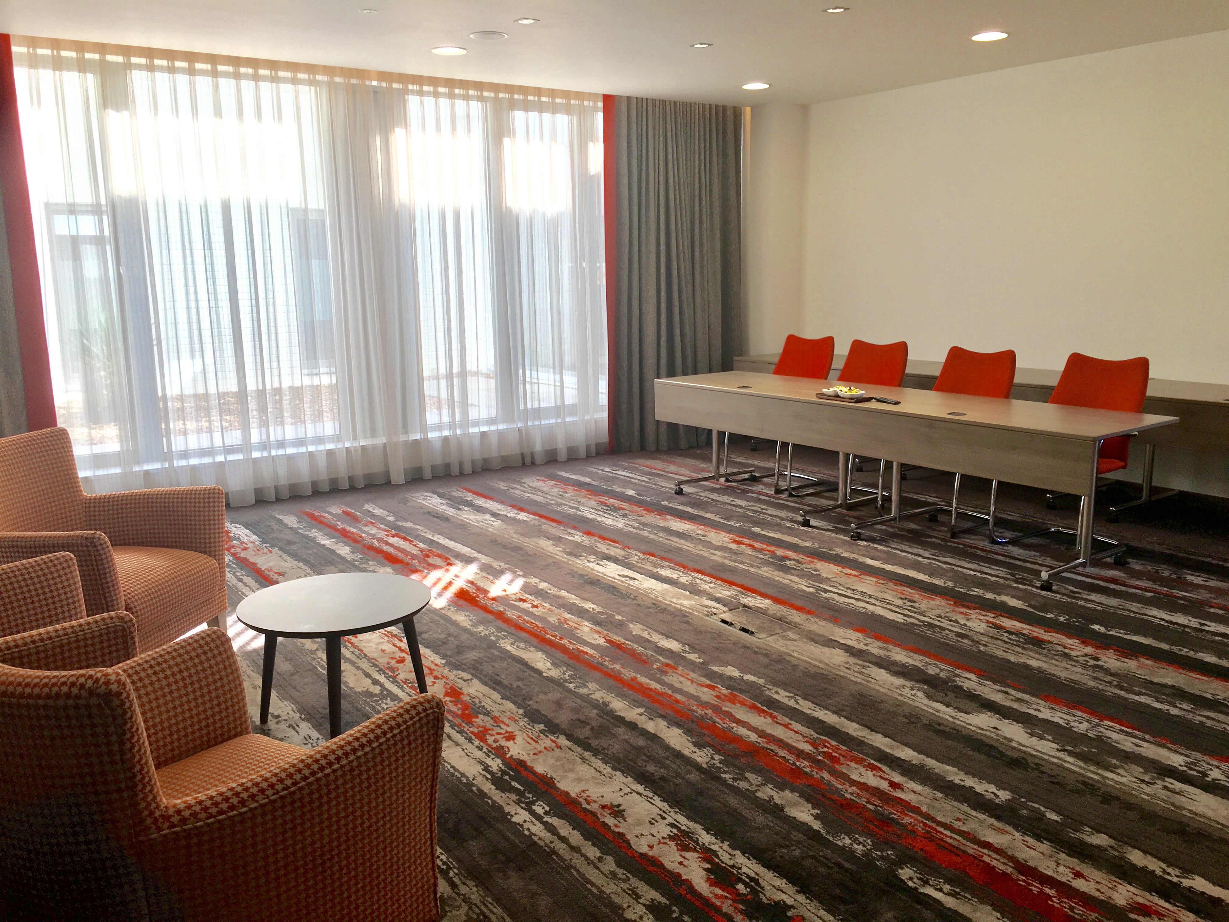 Devonshire Suite at Clayton Hotel Chiswick, modern meeting space with orange chairs.