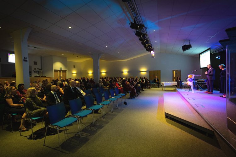 "Corporate event in Riverside Auditorium with engaged audience and speakers on stage"