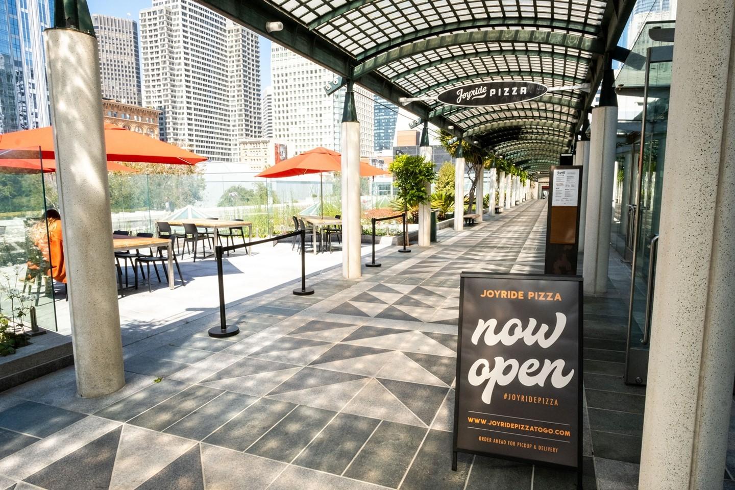 "Outdoor patio with vibrant umbrellas at Joyride Pizza for casual meetings and networking."