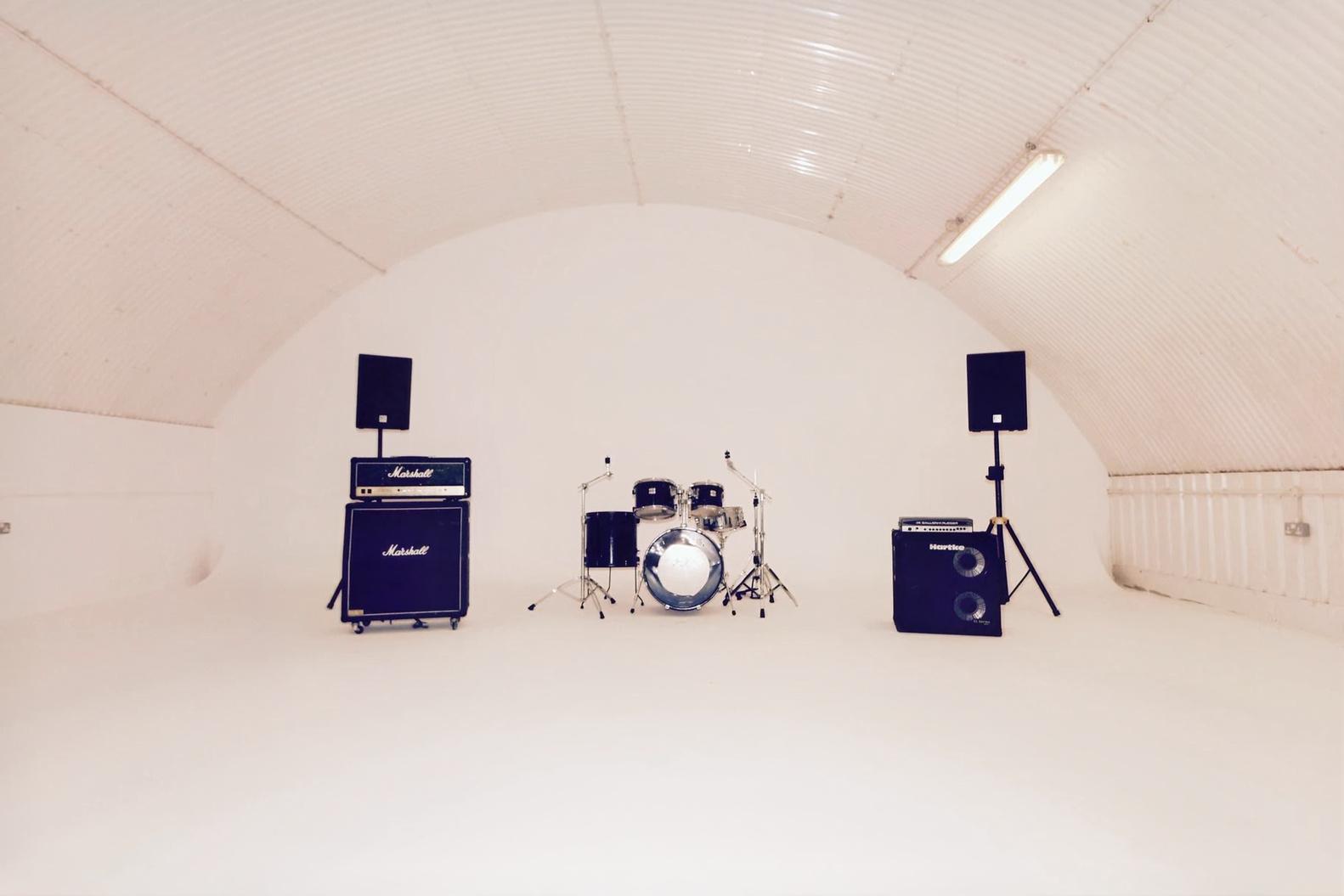 Minimalist music venue in Blue Garage with drum kit, ideal for rehearsals and events.