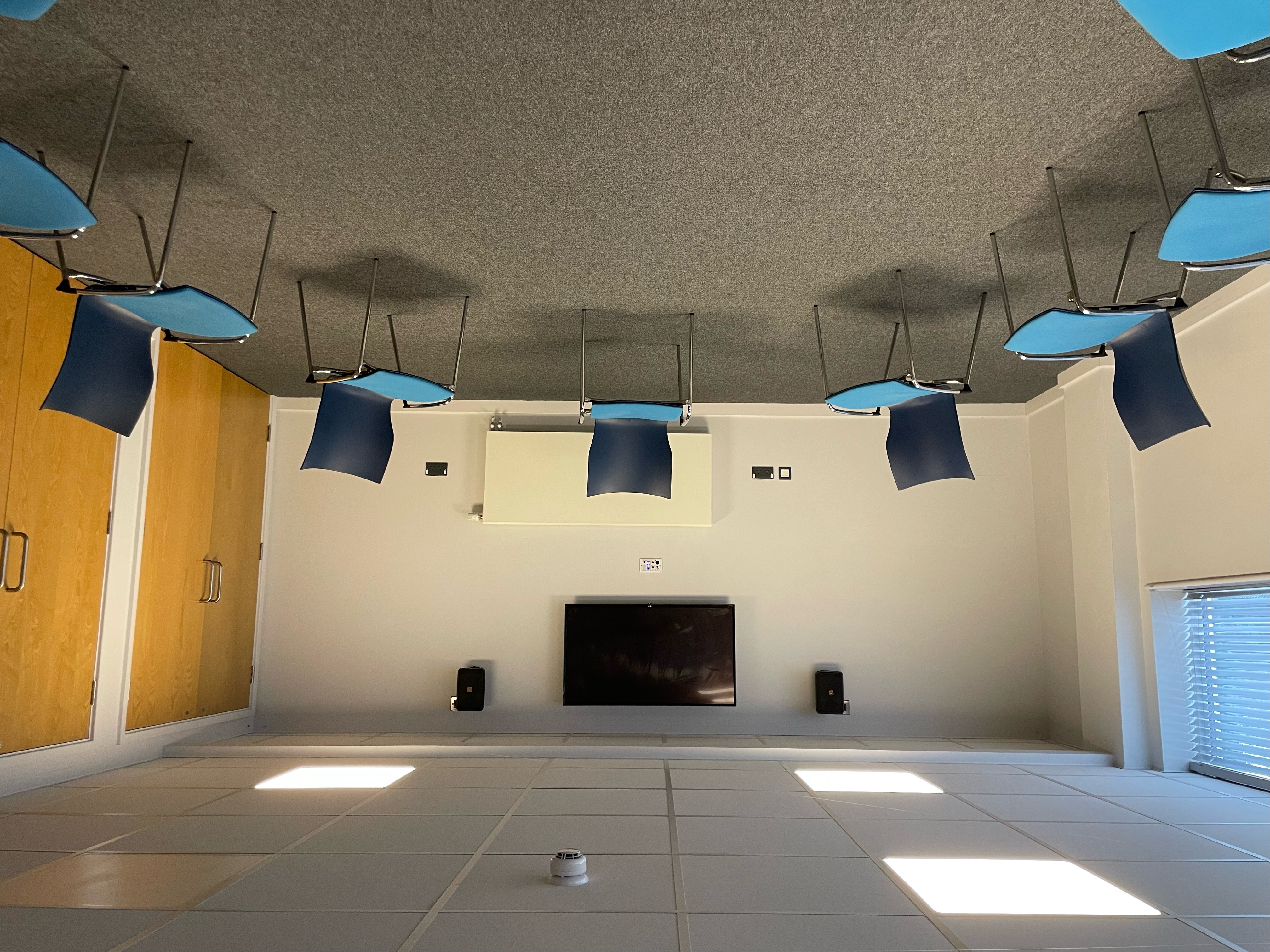 Minimalist meeting room with circle of blue chairs for brainstorming sessions.