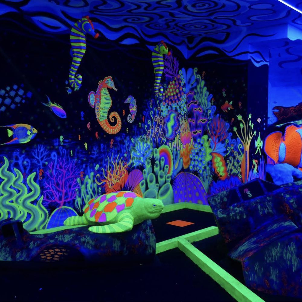 "Underwater-themed mini golf venue with vibrant murals, perfect for creative events."