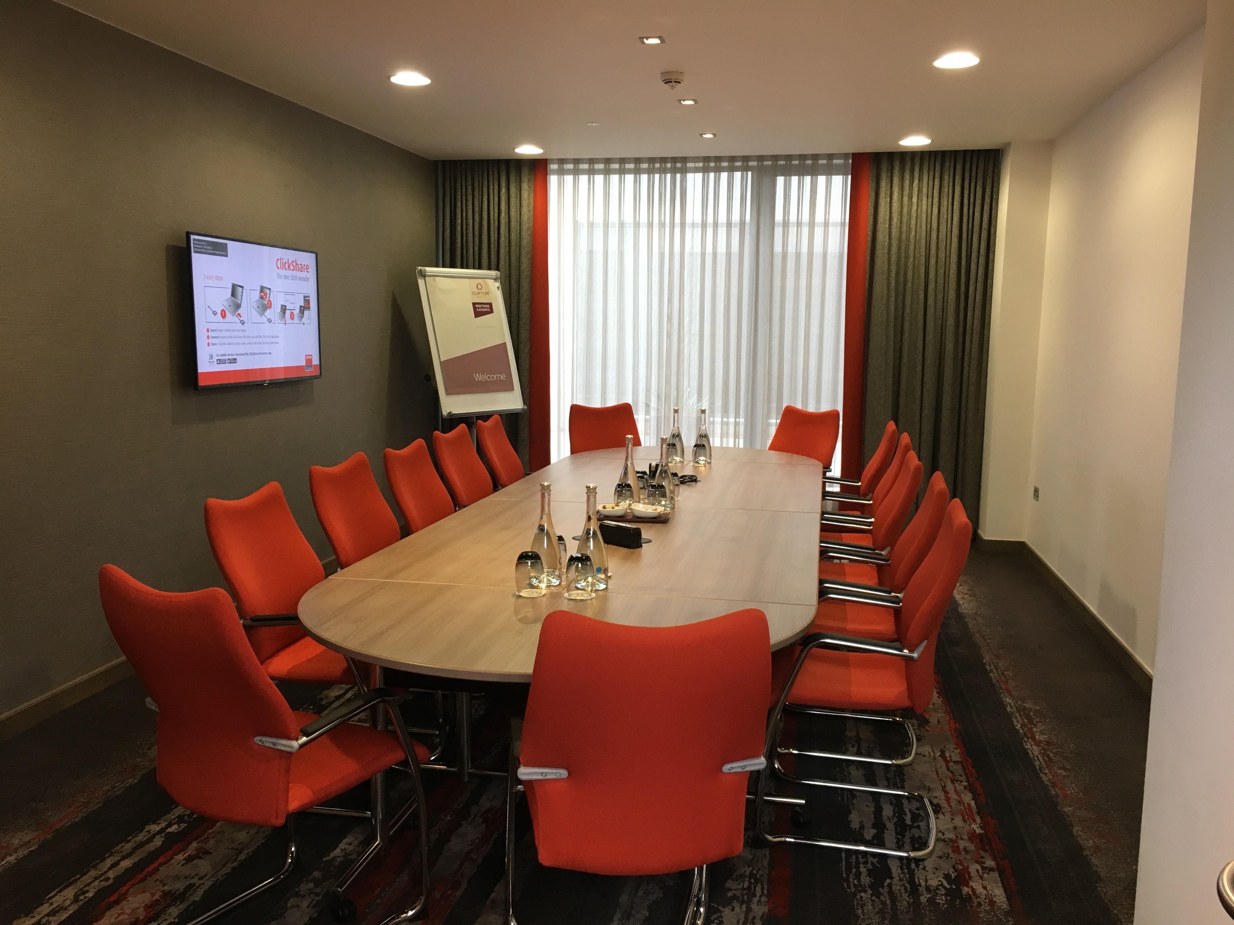 Burlington Suite meeting room with wooden table and orange chairs at Clayton Hotel Chiswick.