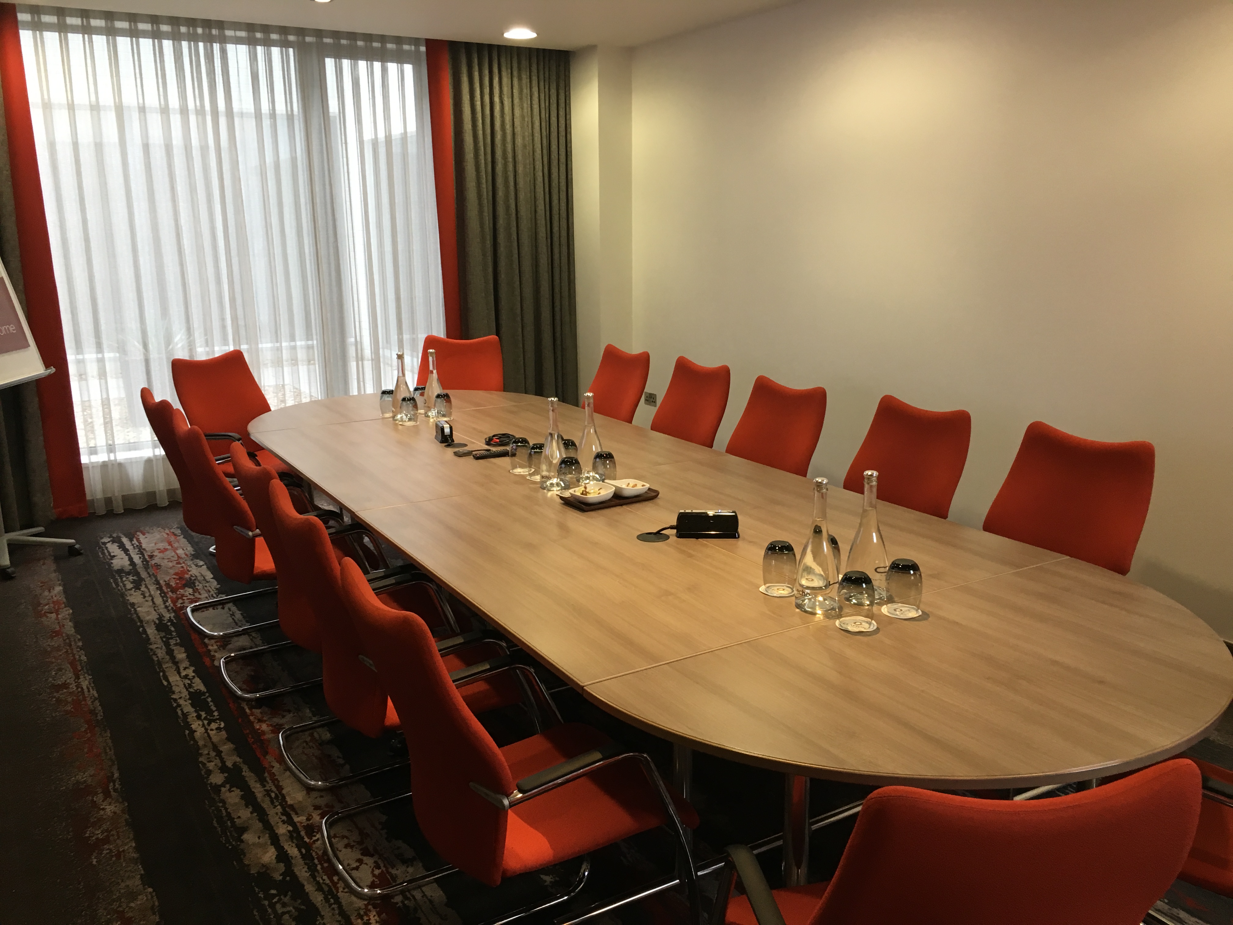 Burlington Suite conference room with oval table and orange chairs, ideal for meetings.