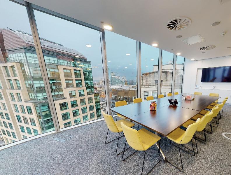 Modern meeting room in Anchorage with yellow chairs and city views, perfect for presentations.
