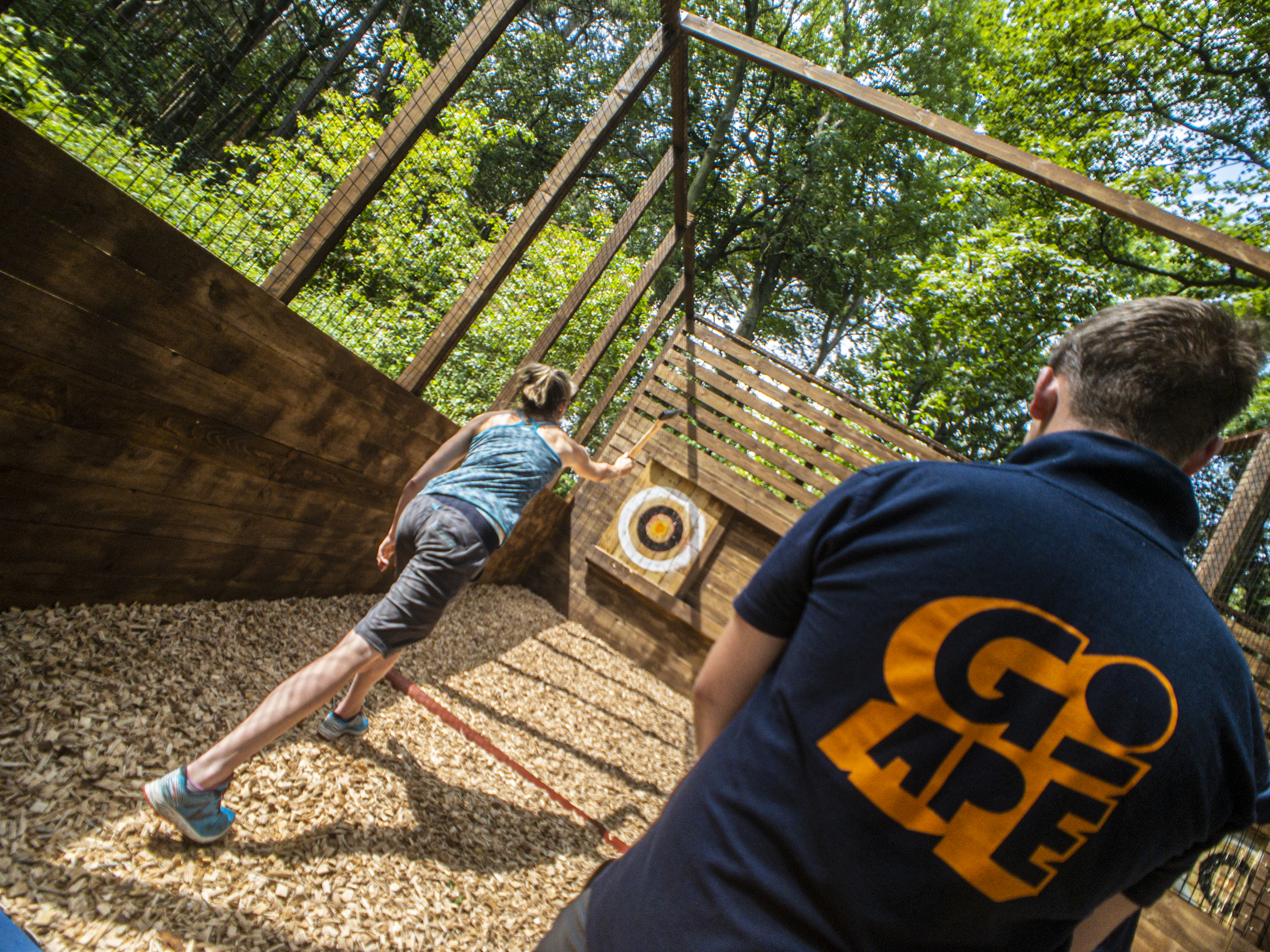 Axe throwing team-building event in nature, showcasing focus and collaboration skills.