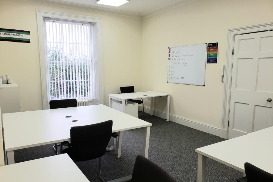 Meeting room with white furniture, ideal for workshops and brainstorming sessions.