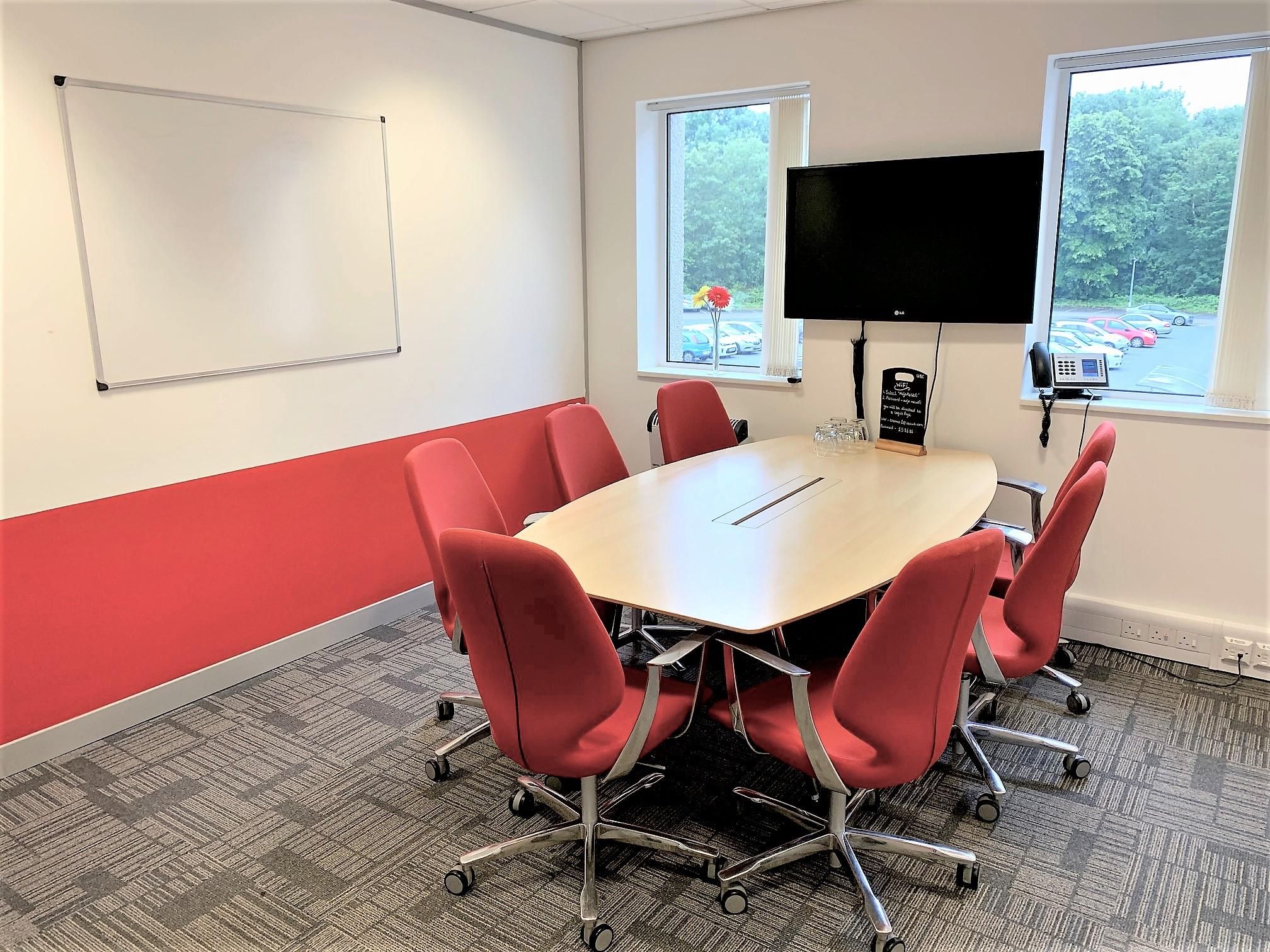 Modern meeting room with oval table and ergonomic red chairs at UBC Flexible Offices.