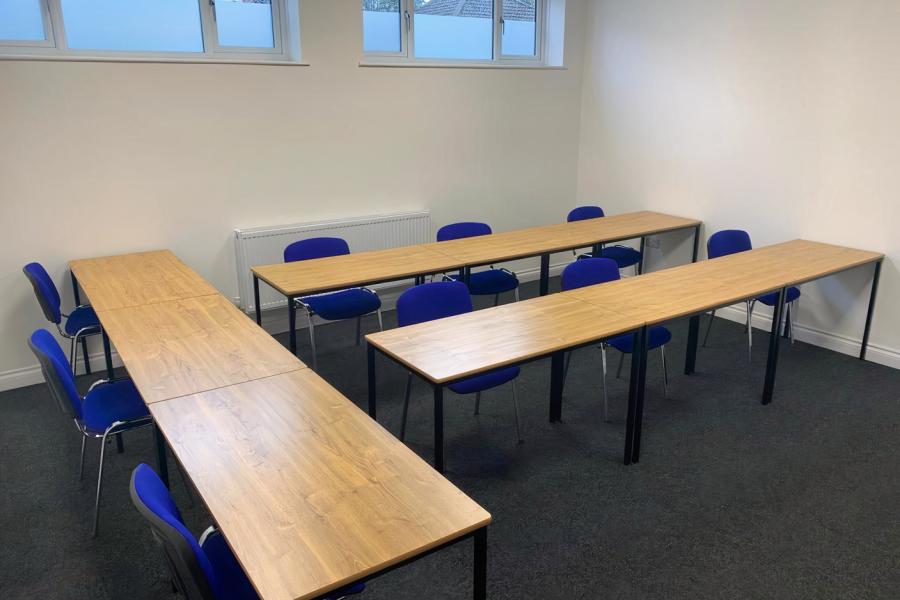 "Bridge School Board Room with U-shaped tables and blue chairs for workshops"