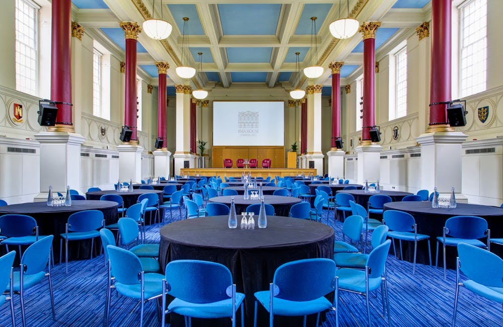 Conference room with round tables and blue chairs, perfect for meetings and events.