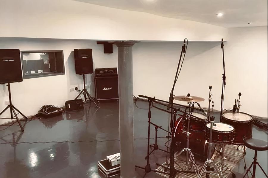 Rehearsal studio with drum kit and sound equipment, perfect for music events and practices.