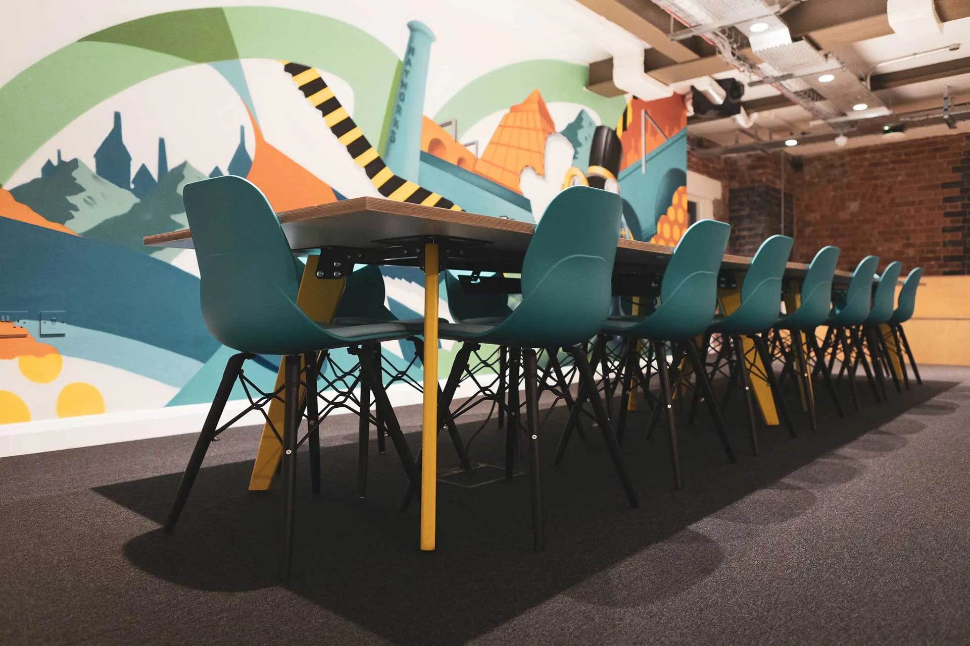 Modern meeting room with stylish table, colorful chairs for creative brainstorming.