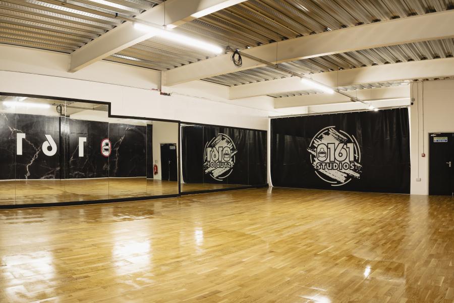 Spacious dance studio with polished wood floors, ideal for classes and events.