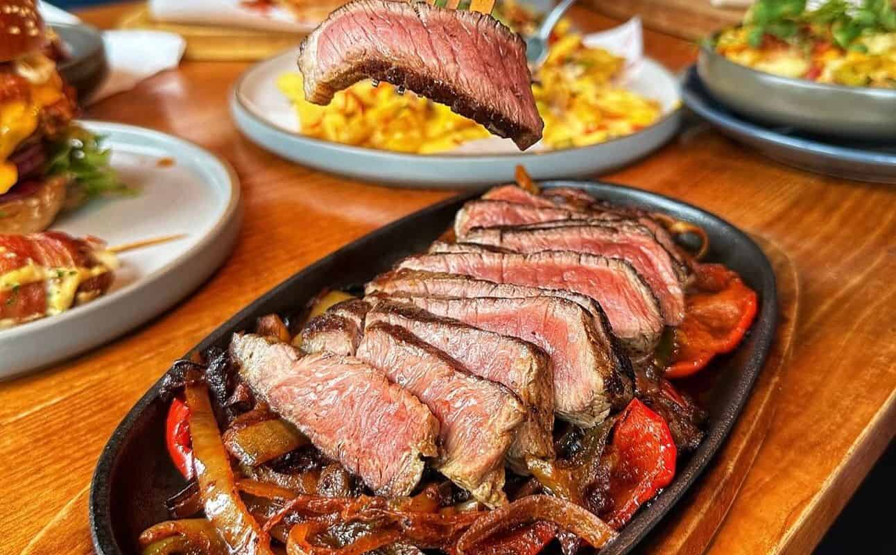 Plated steak dish with sautéed vegetables at The Portland Bar and Grill dining area.