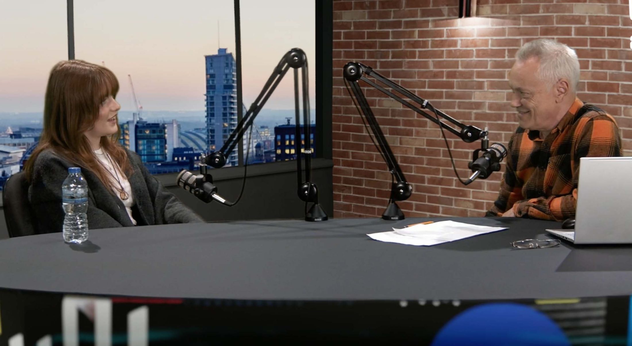 Modern podcast studio with city skyline backdrop for interviews and live streaming.