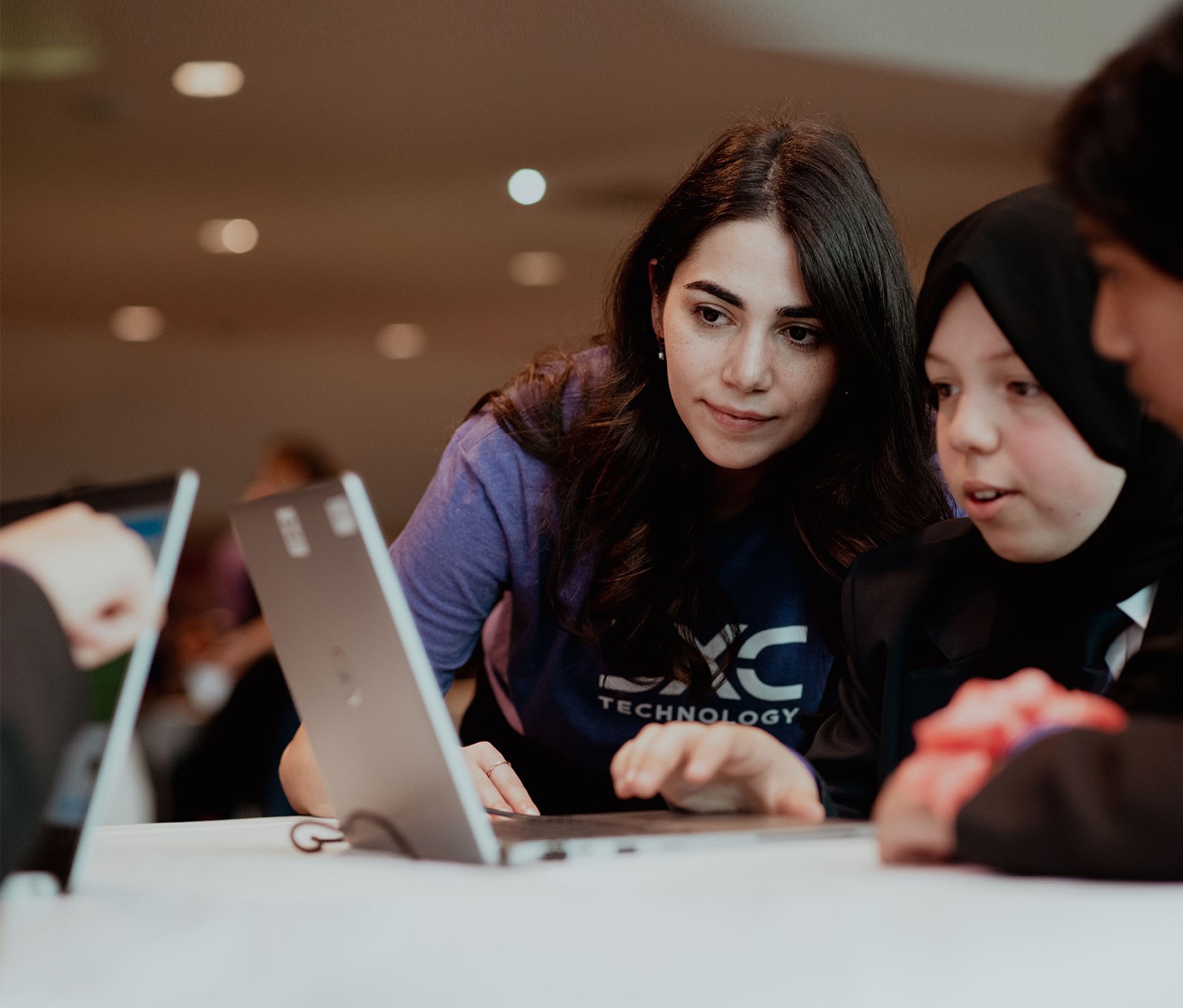 Mentor guiding youth at a technology education event, highlighting hands-on learning.