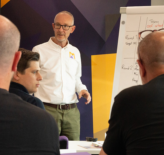 Facilitator engaging audience in collaborative workshop with flip chart. Education event.