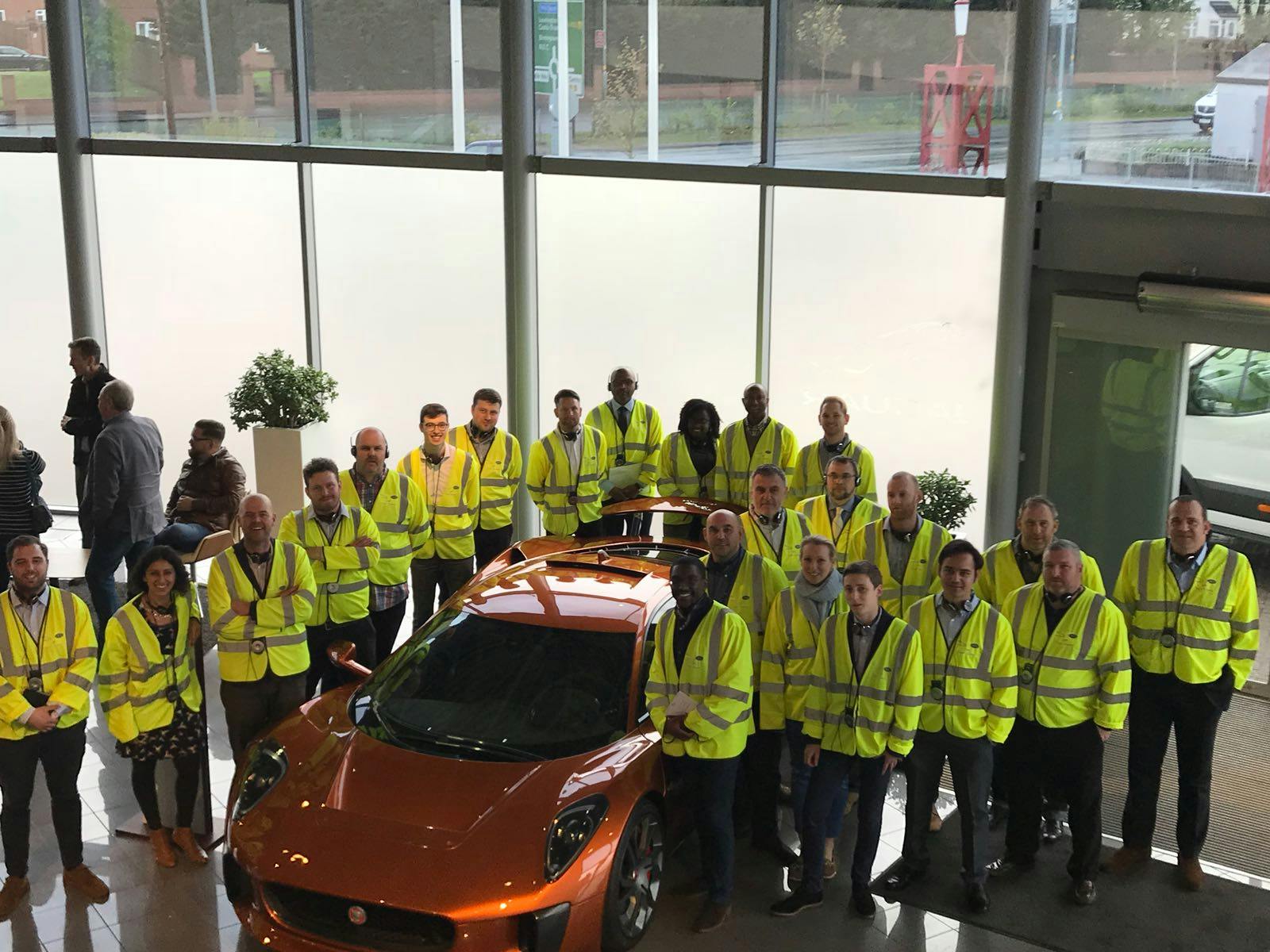 Diverse professionals in safety vests at an automotive innovation networking event.