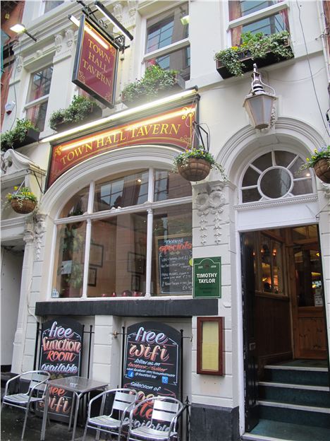 Cozy Town Hall Tavern bar with hanging plants, perfect for informal networking events.