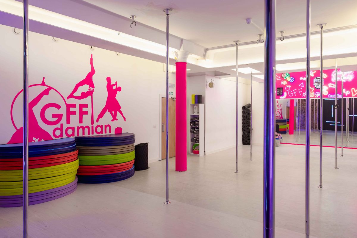 Vibrant dance studio with polished poles, ideal for wellness workshops and fitness events.