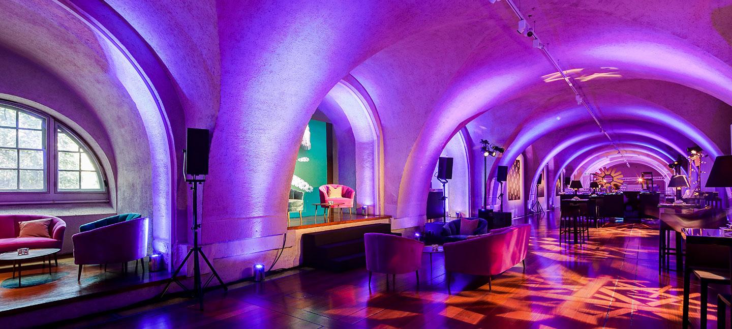 Chic event space with elegant arches and purple lighting, perfect for upscale gatherings.